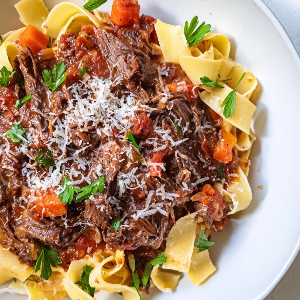 Enticing photo of flavorful slow cooker beef ragu, spooned over perfectly cooked pappardelle pasta.