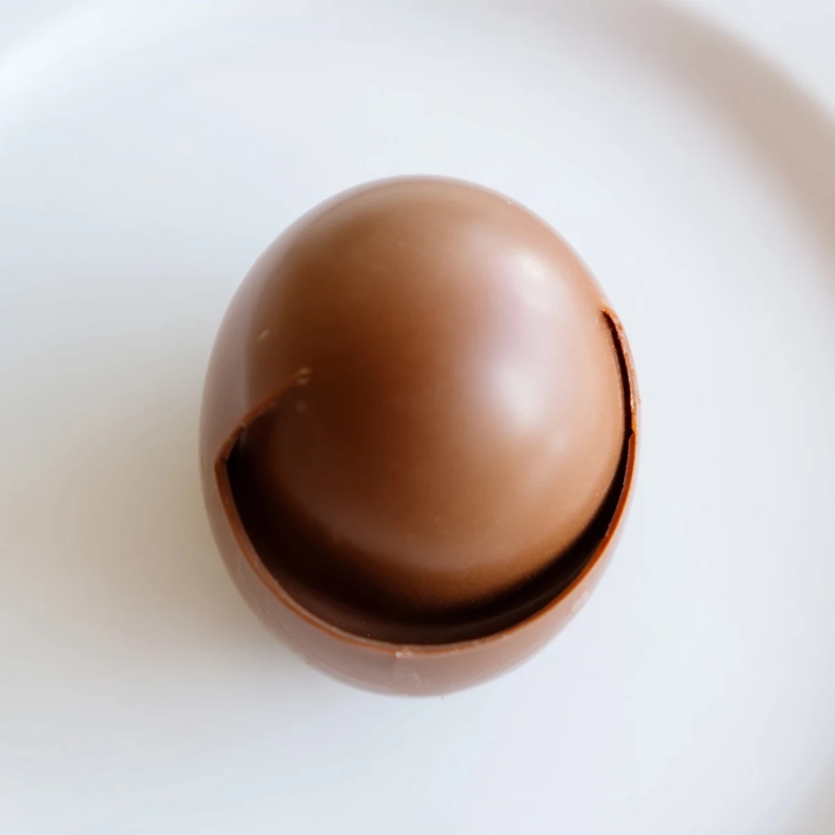 A finished Chocolate Egg with Toy sits wrapped in colorful foil, with a tiny plastic prize peeking out from the cracked shell.