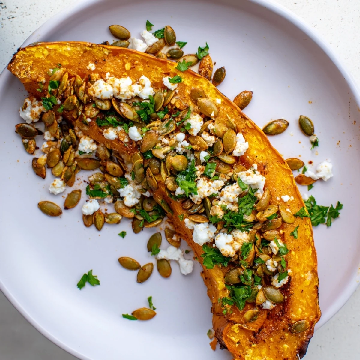 Savory roasted pumpkin with toasted seeds garnished with parsley, served warm as a delicious gluten-free vegetarian side dish.
