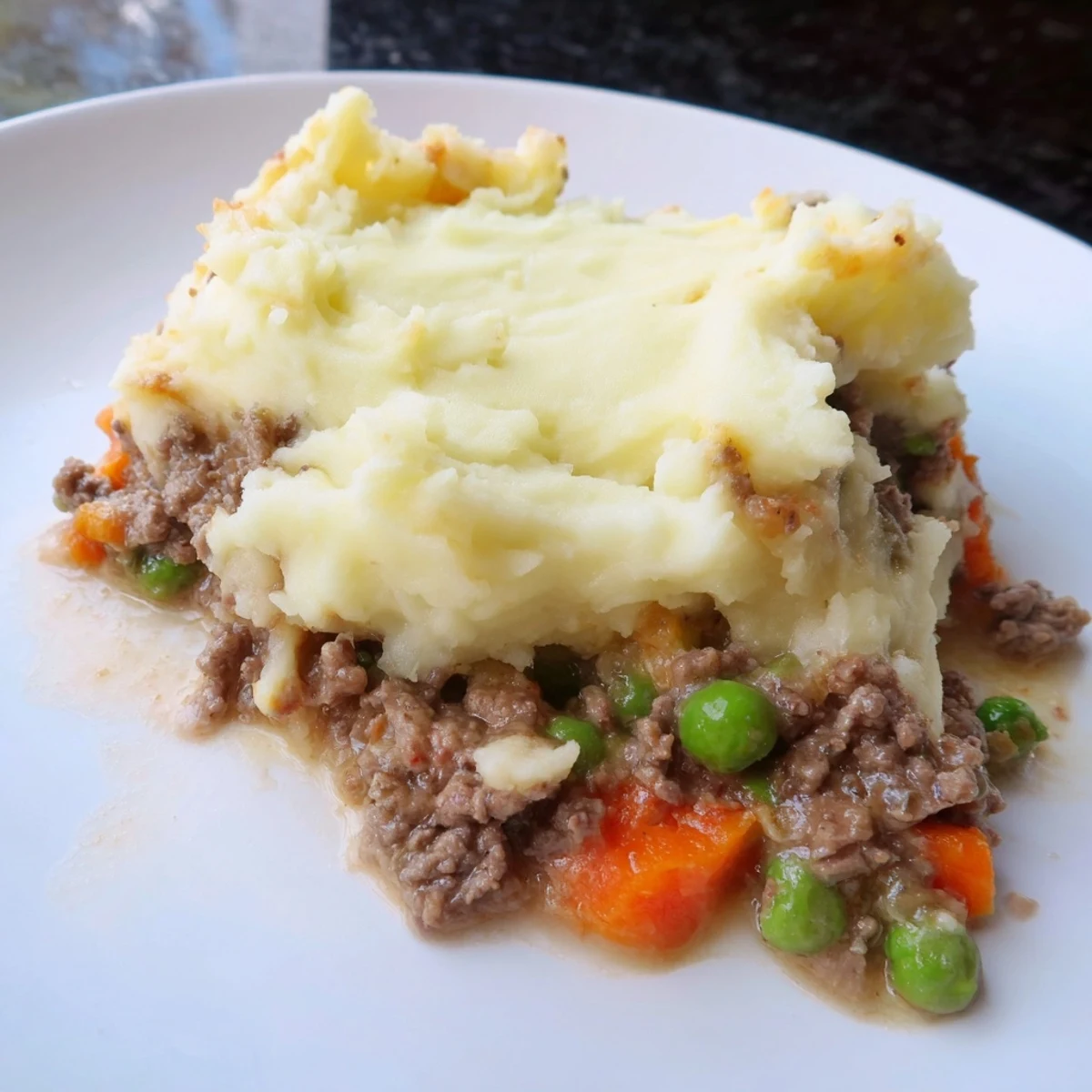 Homemade Beef Shepherds Pie with Peas served in a rustic dish, featuring creamy potatoes and vibrant green peas.