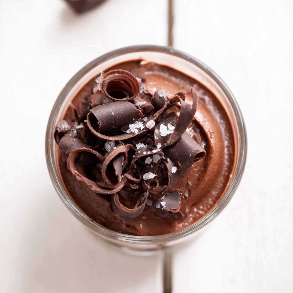 Four elegant glasses of silky dark chocolate mousse, topped with flaky sea salt and chocolate shavings, perfect for a sophisticated gluten-free dessert.