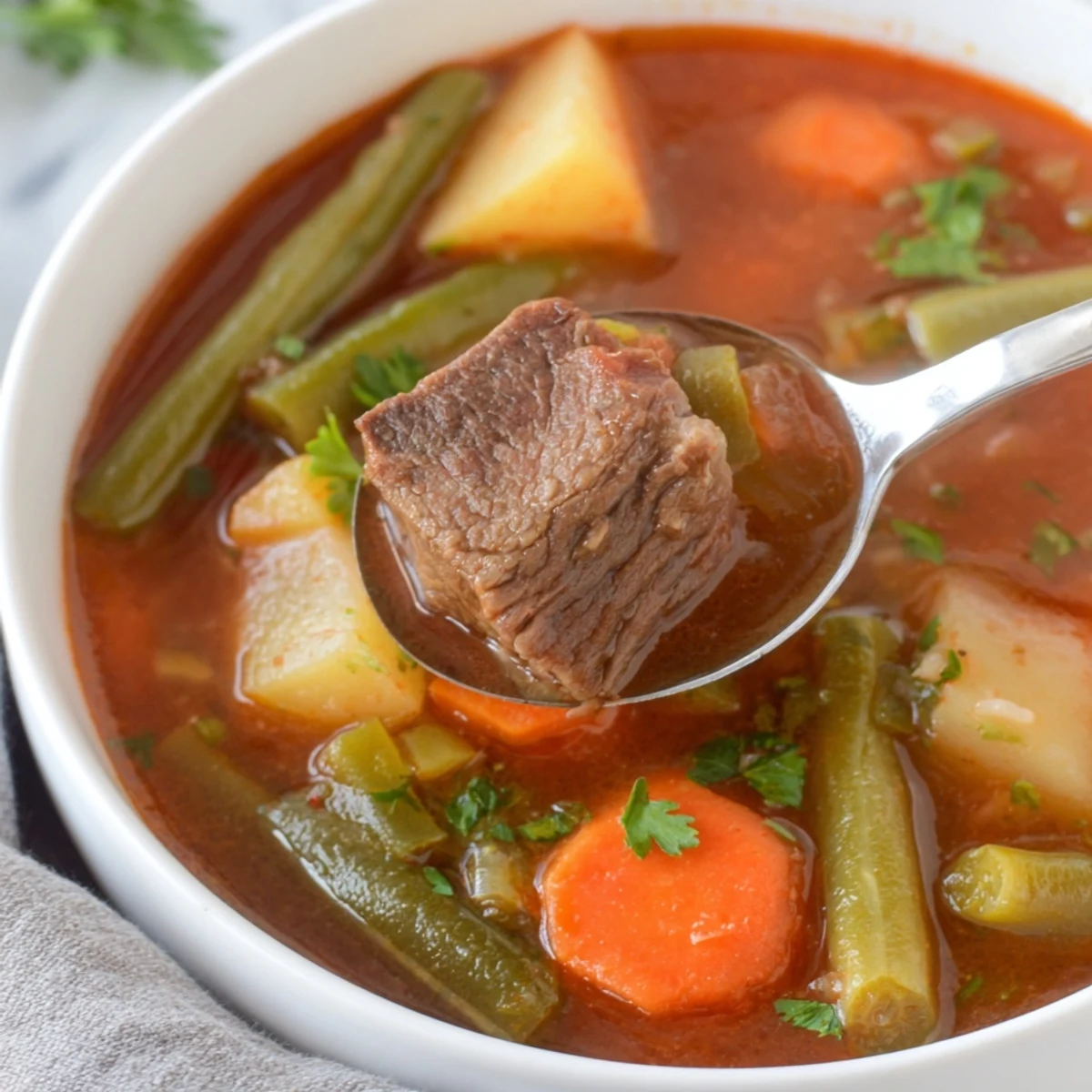 Steaming bowl of Beef Vegetable Soup with Potatoes, featuring tender beef chunks, diced potatoes, and vibrant green beans.