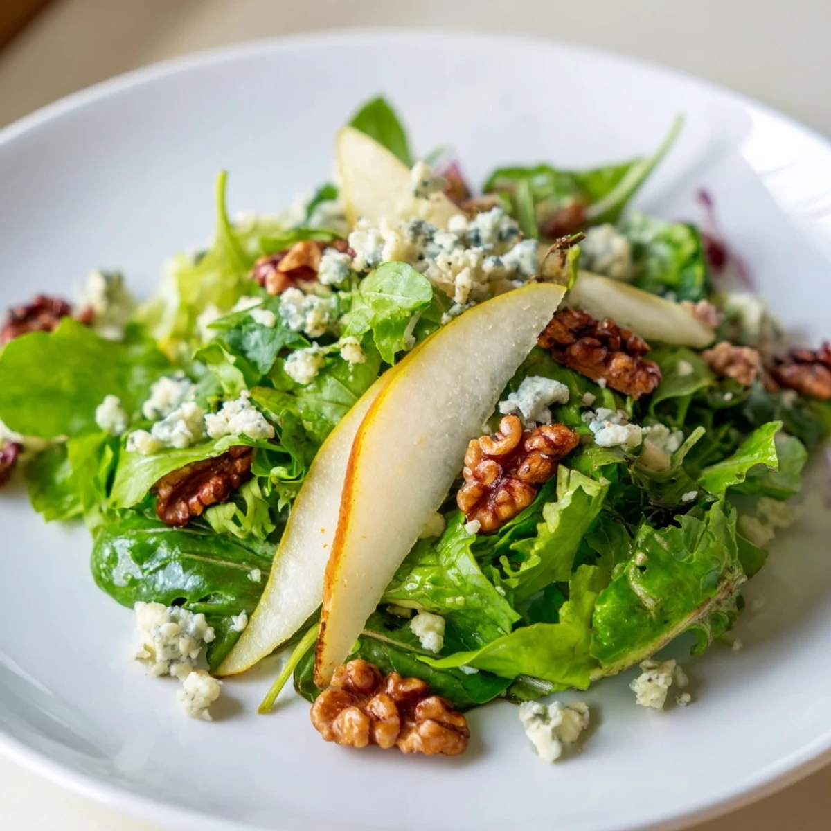 Fresh winter greens topped with sliced pears, candied walnuts, and crumbled blue cheese in a salad bowl.