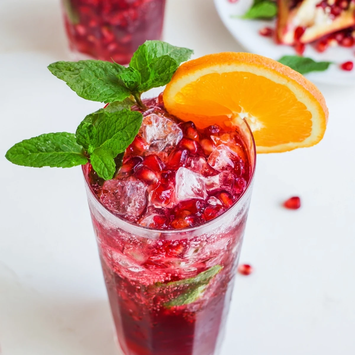 A top-down view of the Love Potion Pomegranate Mocktail Fizz, showing the effervescent bubbles rising through the deep red liquid and a sprig of mint resting on the rim.