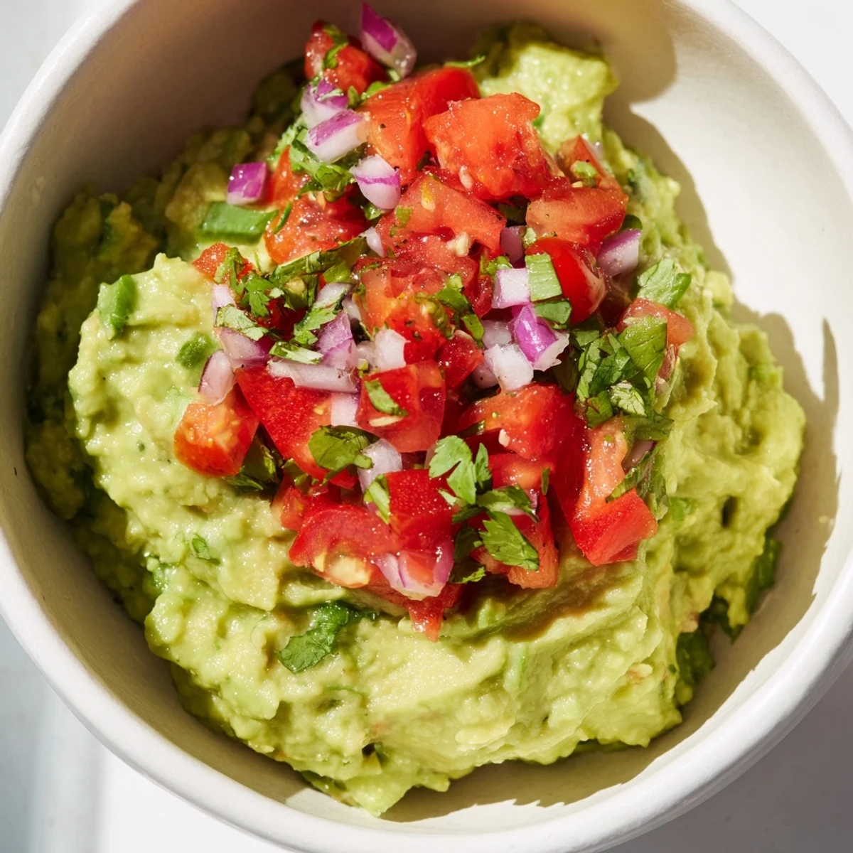 Vibrant Guacamole with Fresh Pico de Gallo in a rustic bowl, ready for a party platter with colorful toppings.