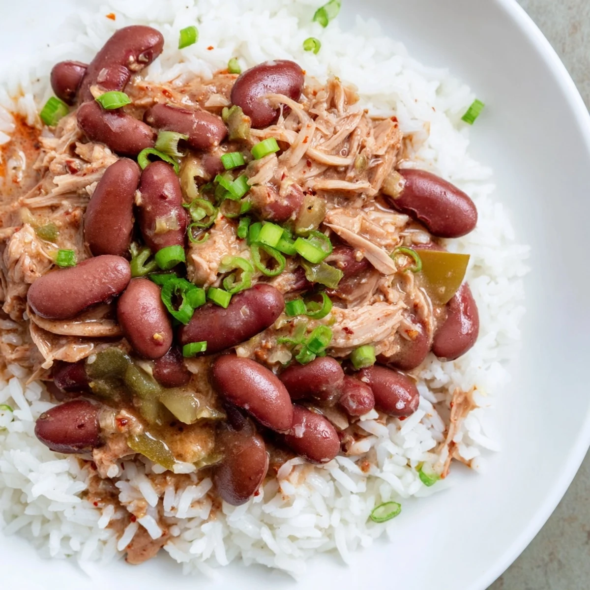 Slow-simmered Creole Red Beans and Rice with Smoked turkey in a rustic pot, topped with fresh sliced green onions.