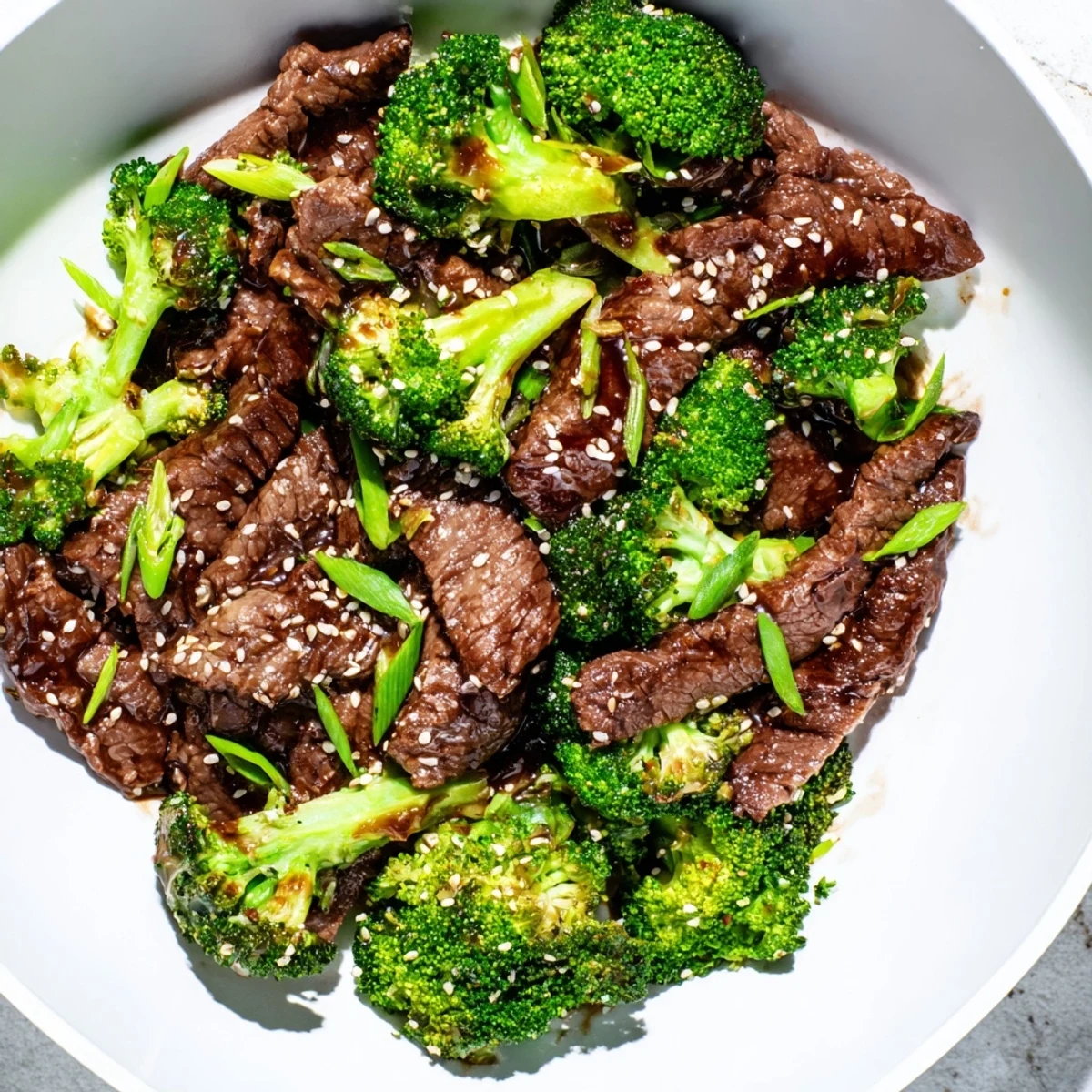 Homemade beef and broccoli stir fry with ginger sauce, garnished with sesame seeds and fresh green onions.