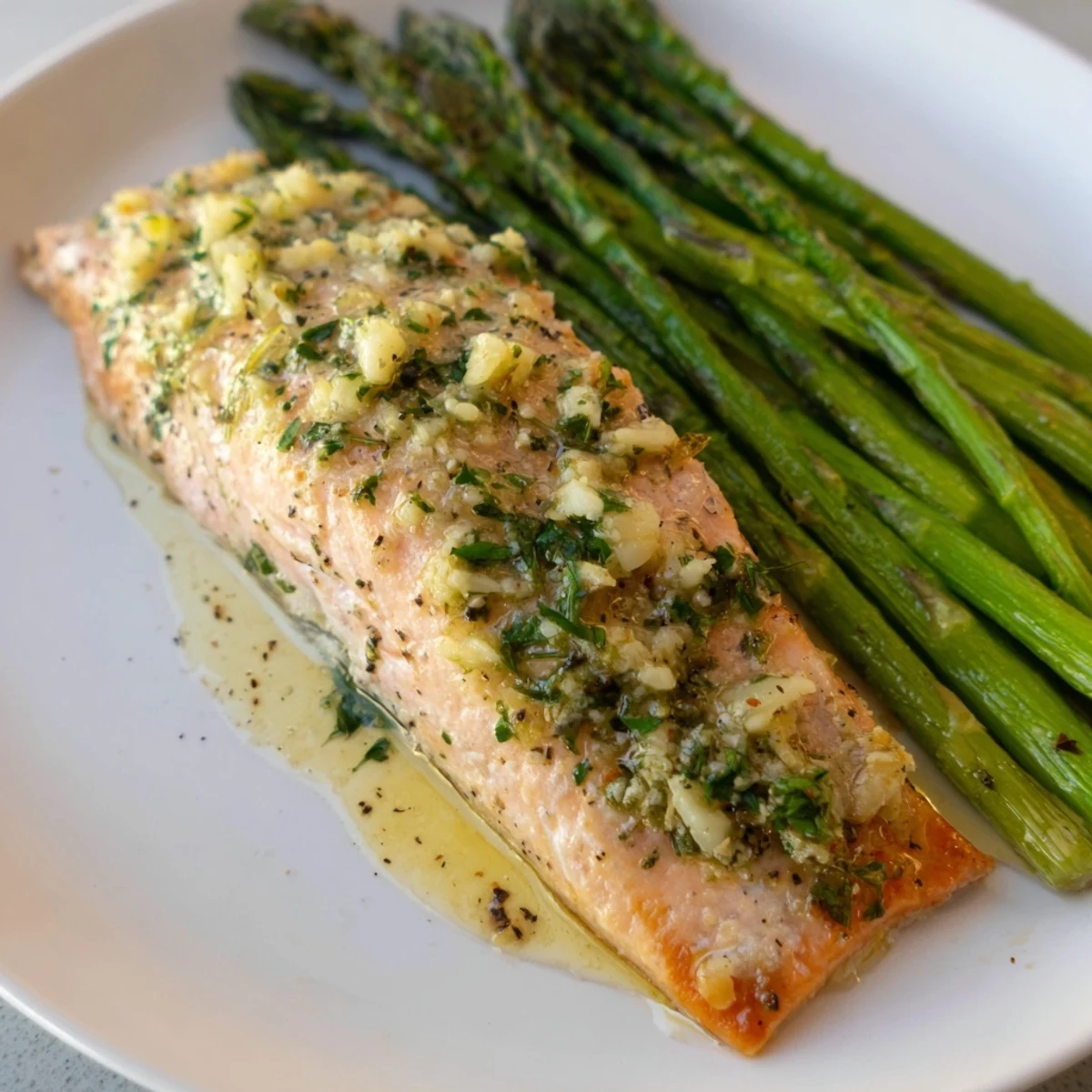 Roasted asparagus spears and salmon fillets topped with a zesty lemon garlic butter sauce, ready to serve.