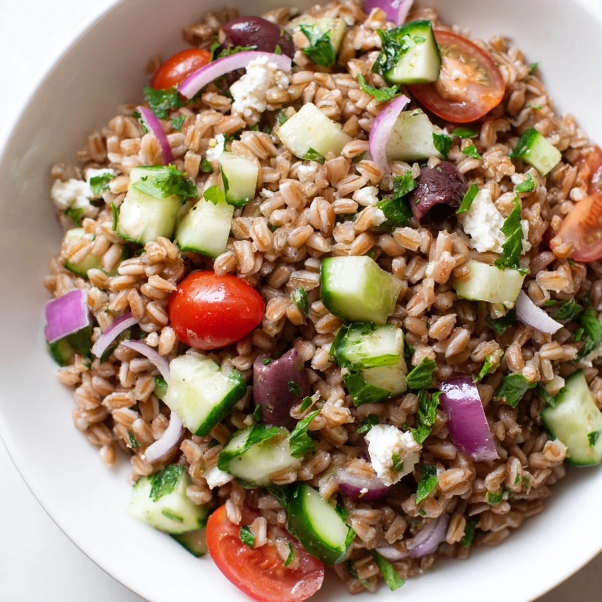 Crisp Mediterranean Farro Salad with cucumber and feta served in a white bowl, perfect for a light summer lunch.