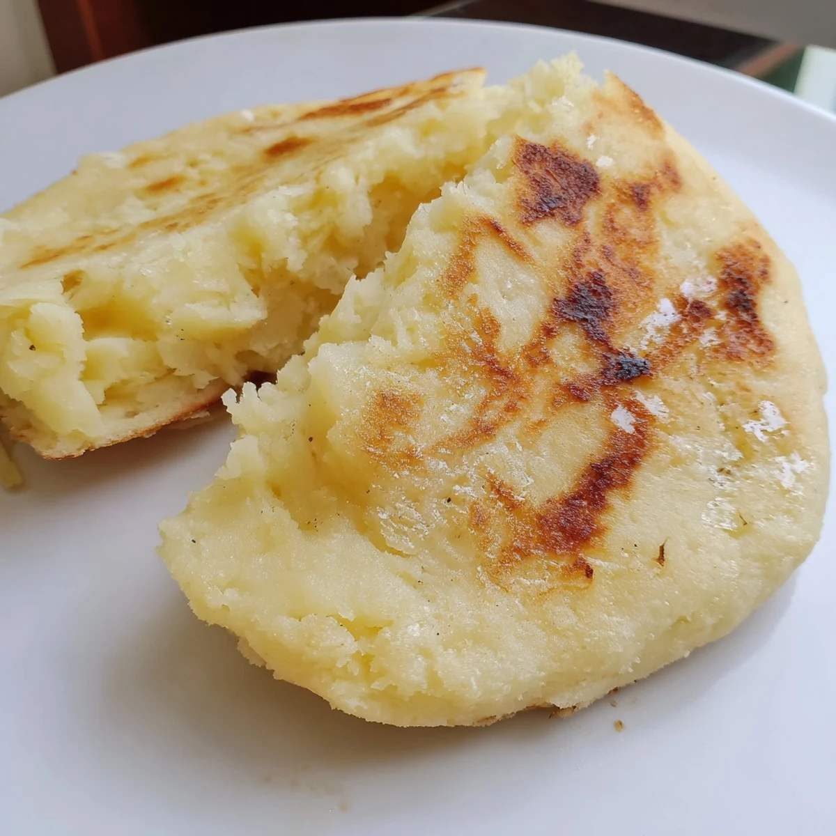 A close-up of freshly cooked Irish Potato Bread Farls with a soft interior and crispy edges on a plate.  