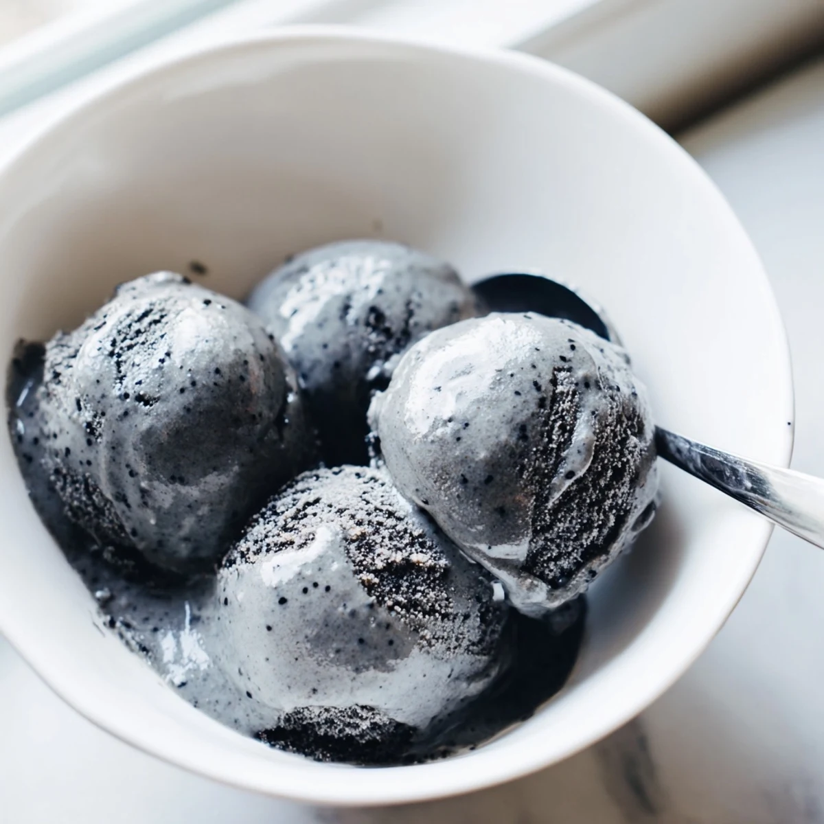A close-up of rich Toasted Black Sesame Ice Cream in a dessert dish, highlighting its smooth texture.