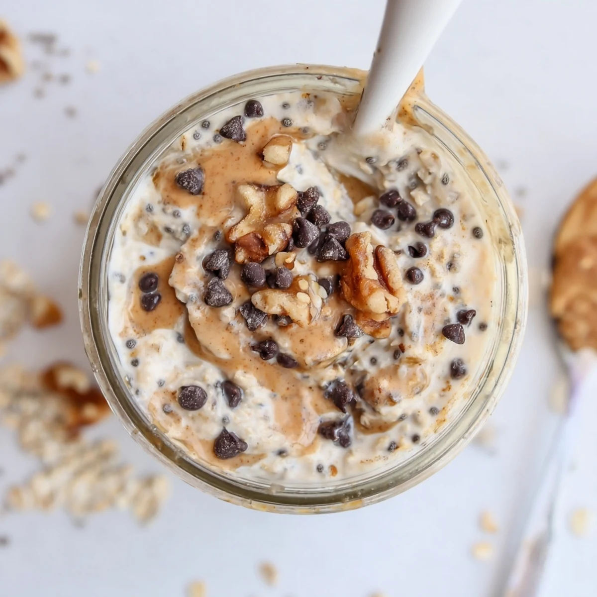 Creamy Cookie Dough Overnight Oats layered with chocolate chips and walnuts served in a glass jar.