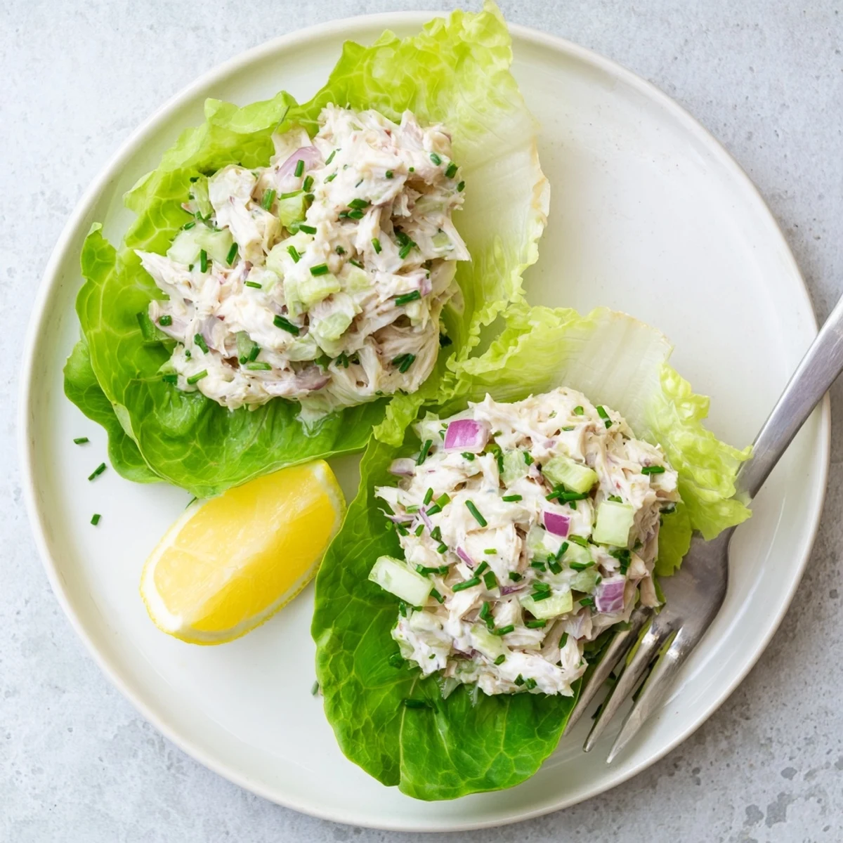 A close-up of the creamy Crab Salad on crisp lettuce leaves, with bright lemon wedges beside it for serving.