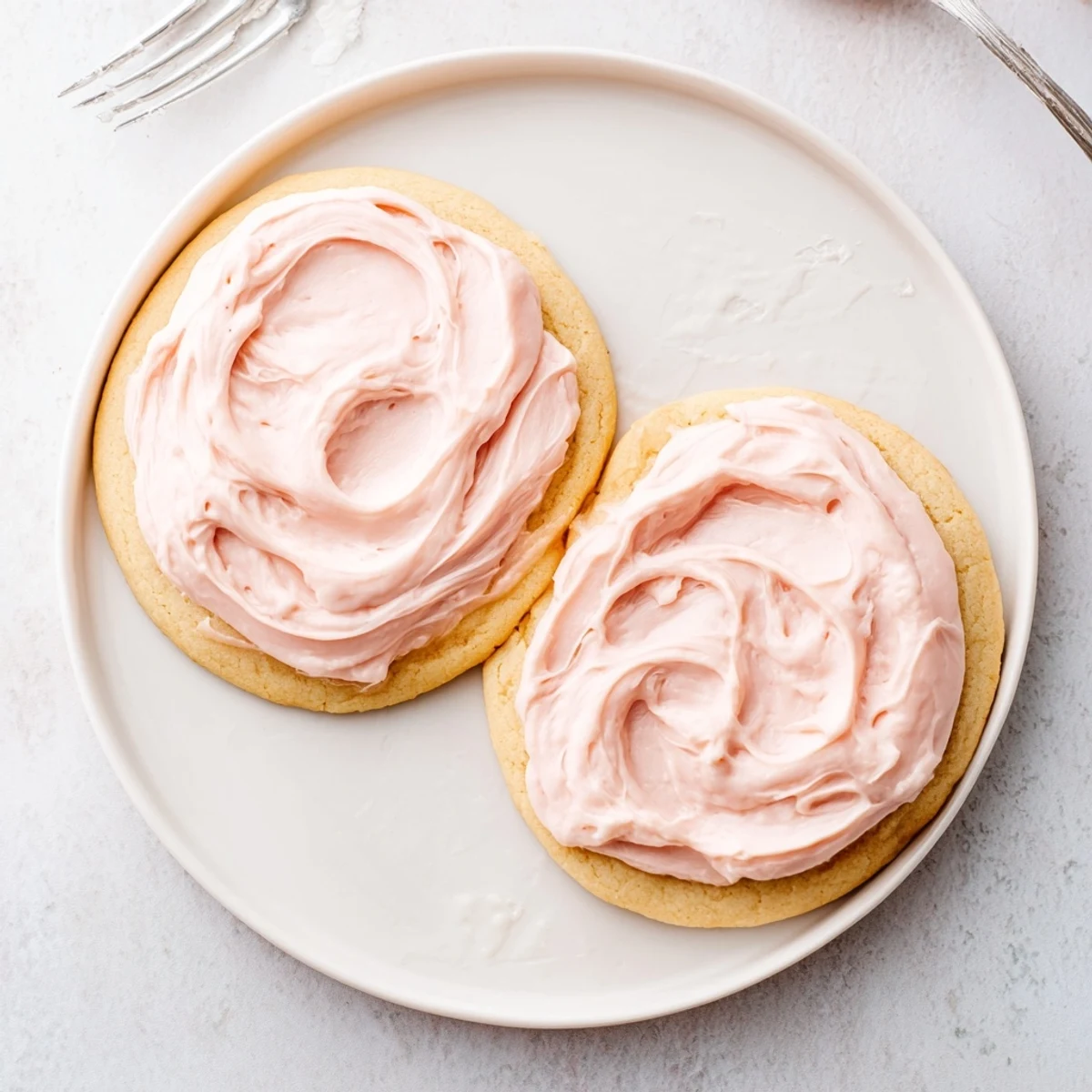 A close-up of a giant sugar cookie with velvety frosting and sprinkles.