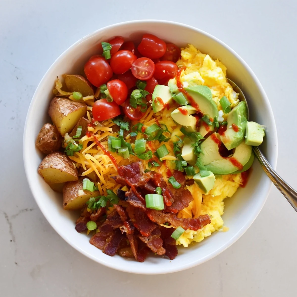 For an American morning, a loaded breakfast bowl features fluffy eggs, savory bacon, and a drizzle of hot sauce.