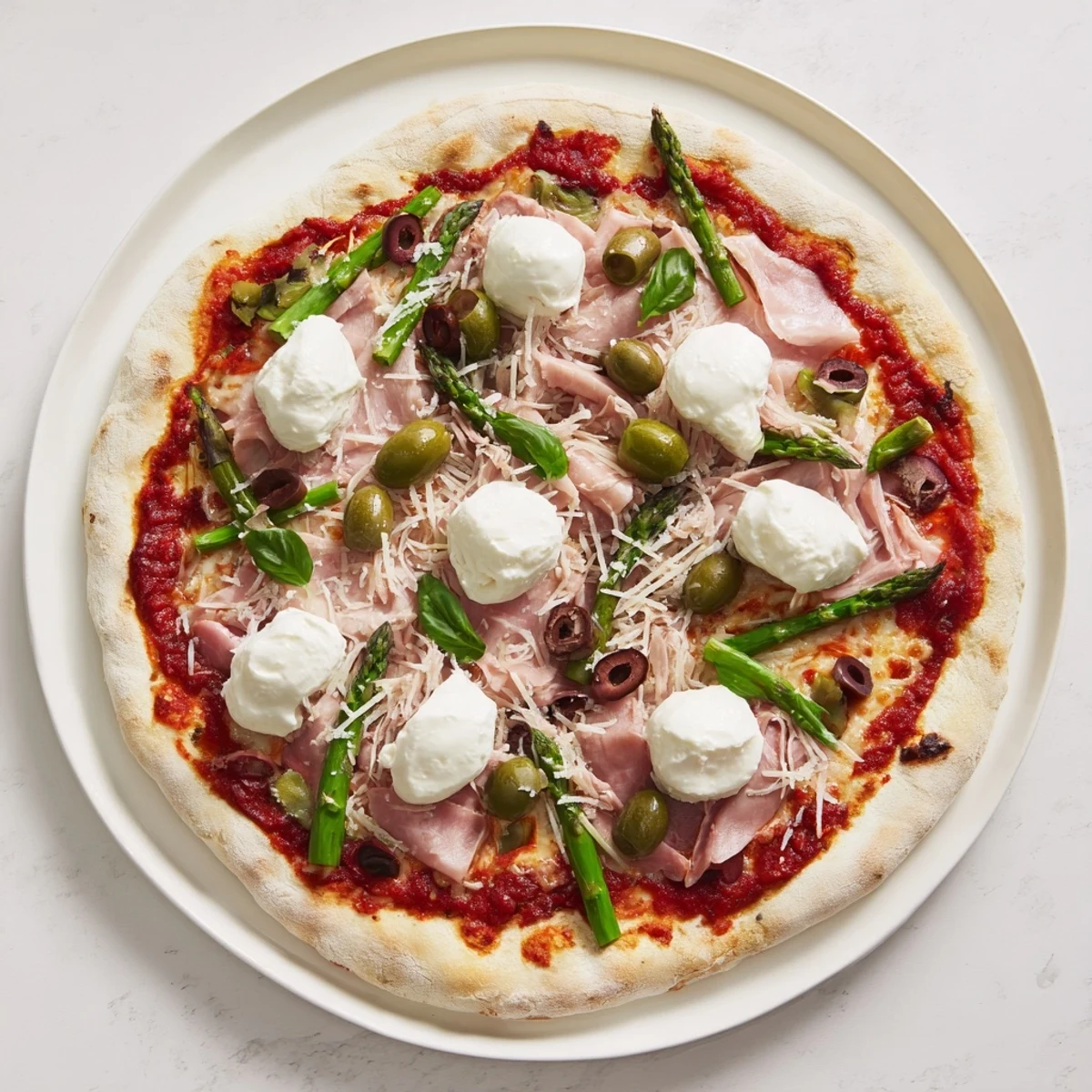 Golden, crisp pizza with smoky ham, briny olives, tender asparagus, and dollops of creamy ricotta, baked and ready to slice and serve.