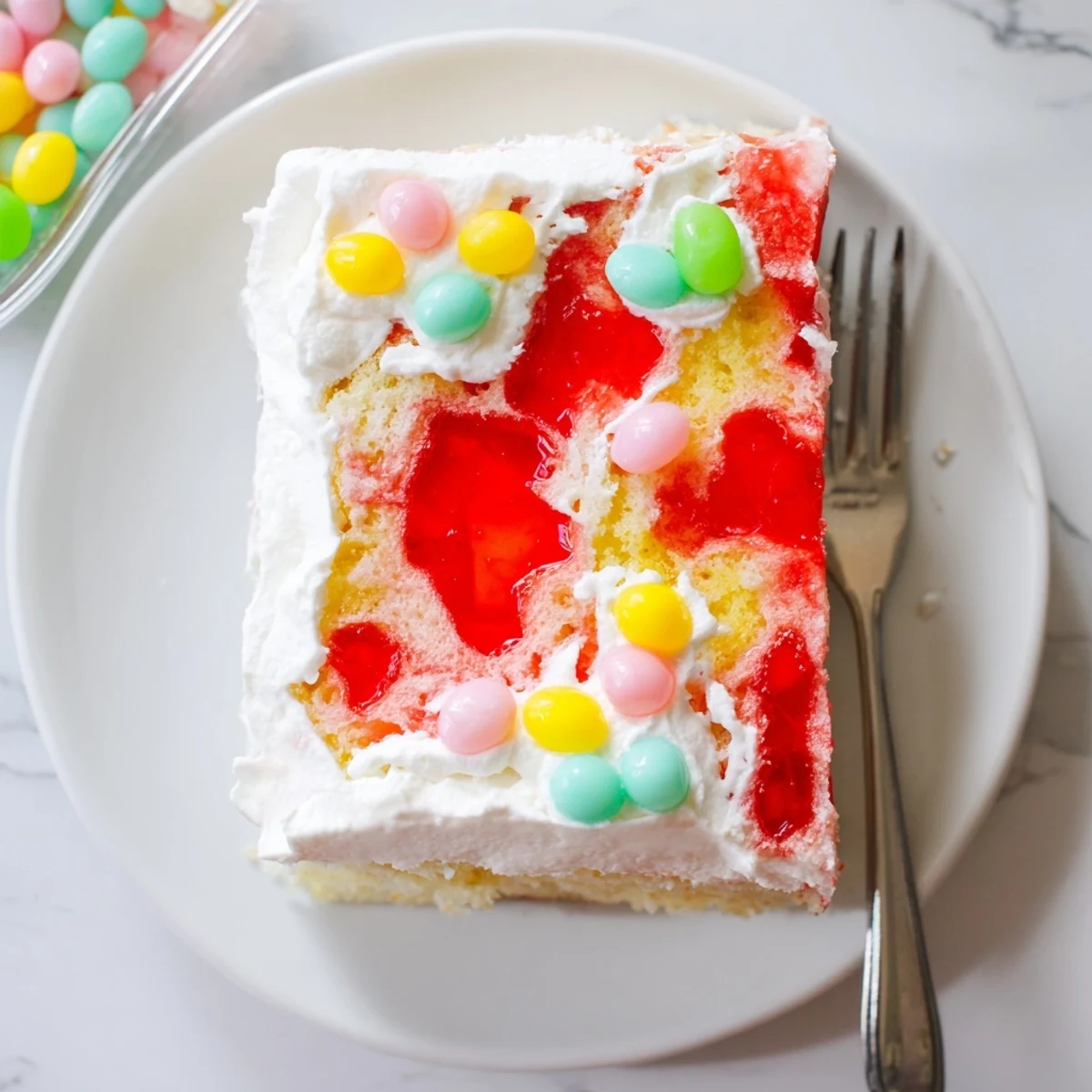 A serving of Easter Poke Cake with Vanilla Gelatin and Fruity Topping on a dessert plate with a side of fresh berries.