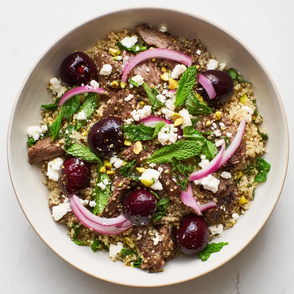 Protein-rich cherry quinoa salad with lamb served on arugula with zesty lemon dressing