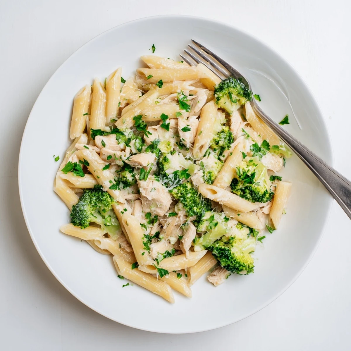 Creamy rotisserie chicken broccoli pasta tossed in garlic Parmesan sauce with fresh parsley garnish
