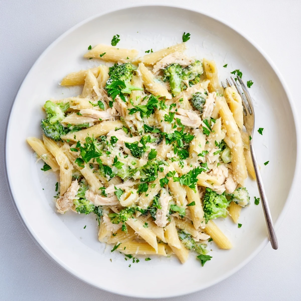 Steamy bowl of rotisserie chicken broccoli pasta penne coated in rich white cheesy sauce