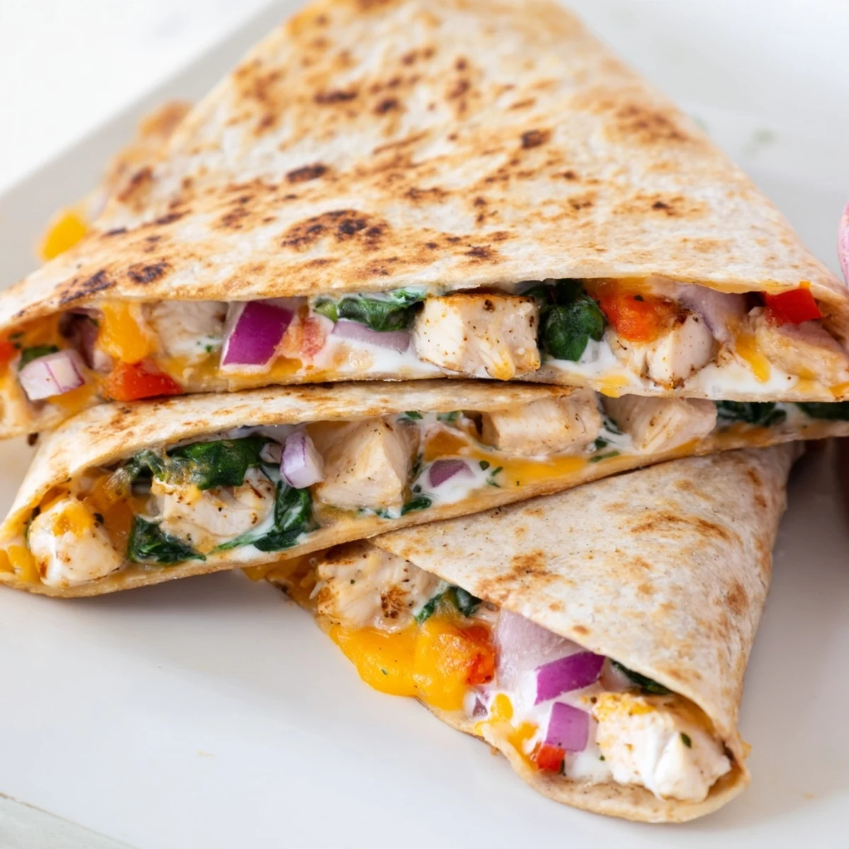 Golden brown high protein chicken ranch quesadilla sliced into wedges on a white plate