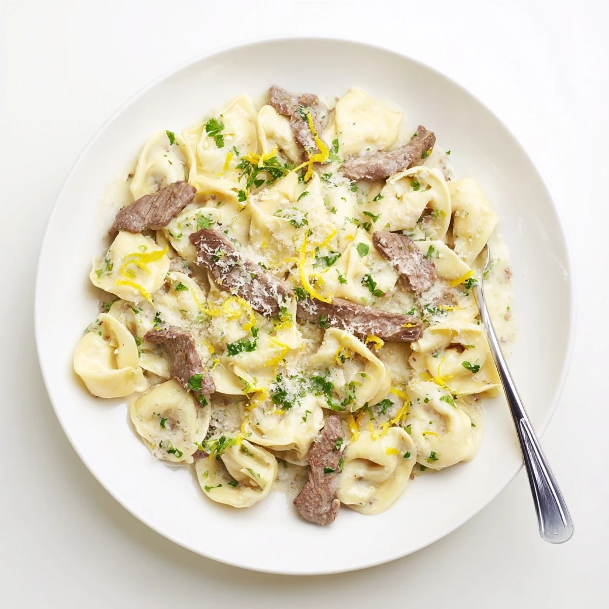 Creamy garlic steak tortellini plated with fresh parsley and cracked black pepper garnish