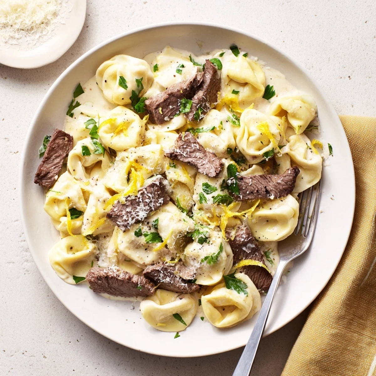 Golden seared steak slices atop cheese tortellini swimming in rich garlic cream sauce