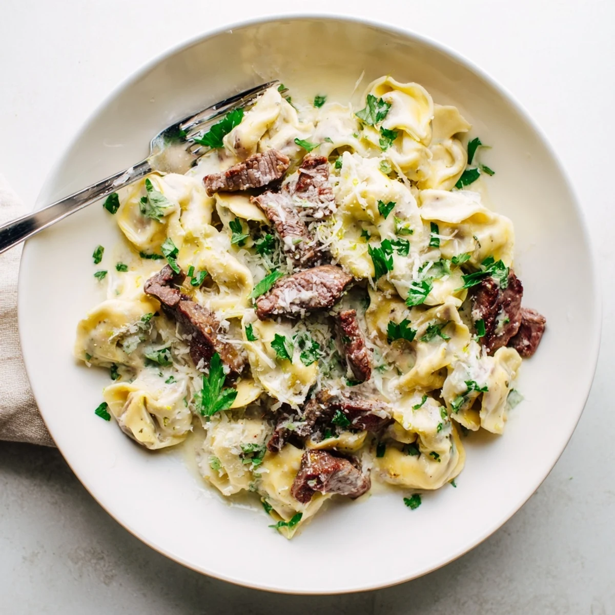 Decadent cracked garlic steak tortellini in silky white sauce with lemon zest and Parmesan