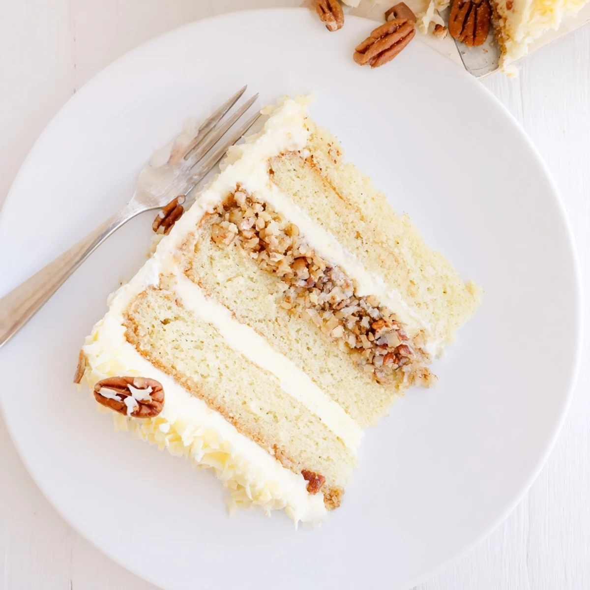Slice of white German chocolate cake revealing creamy coconut-pecan filling between moist white layers