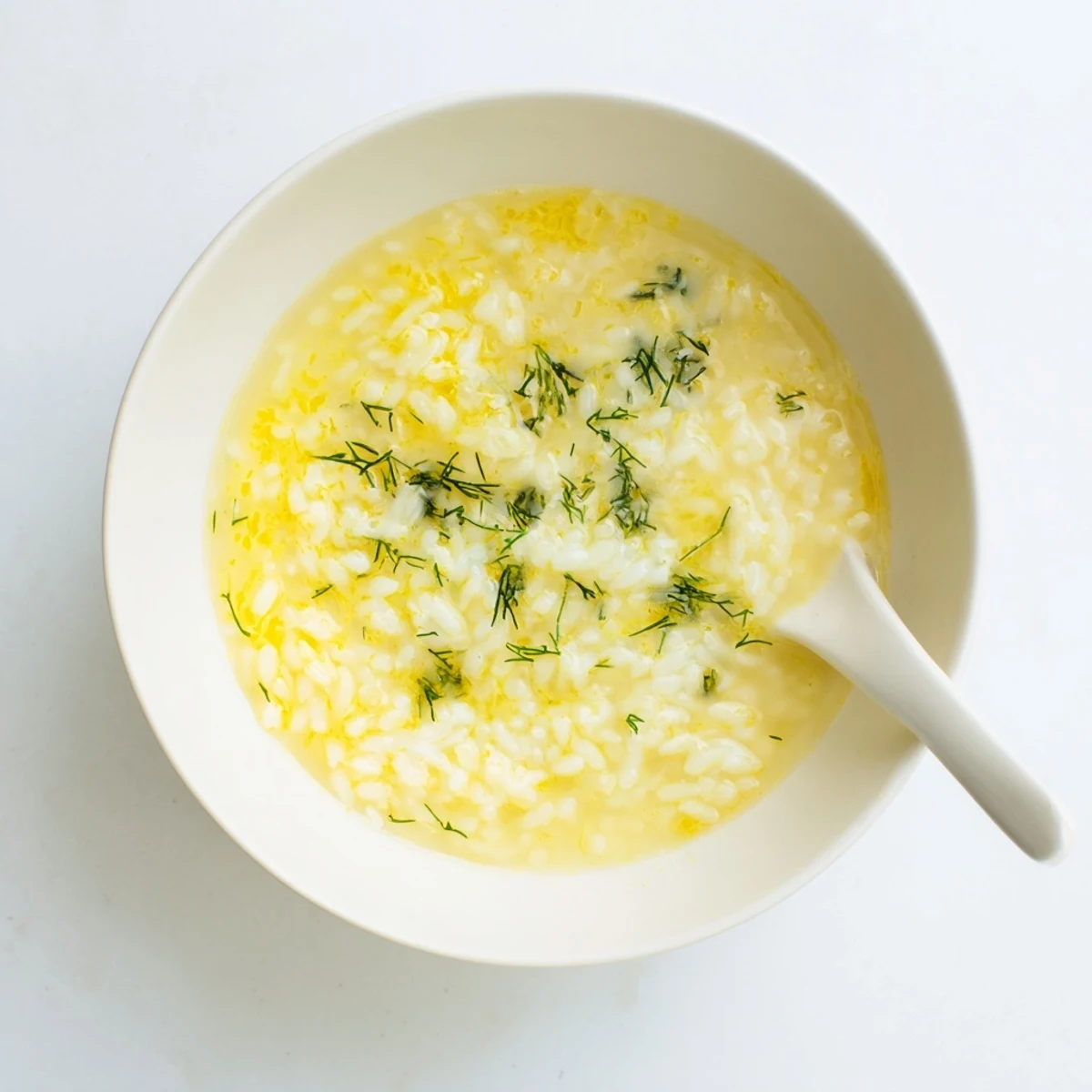 Steaming bowl of traditional Greek egg and lemon soup with chopped parsley on top