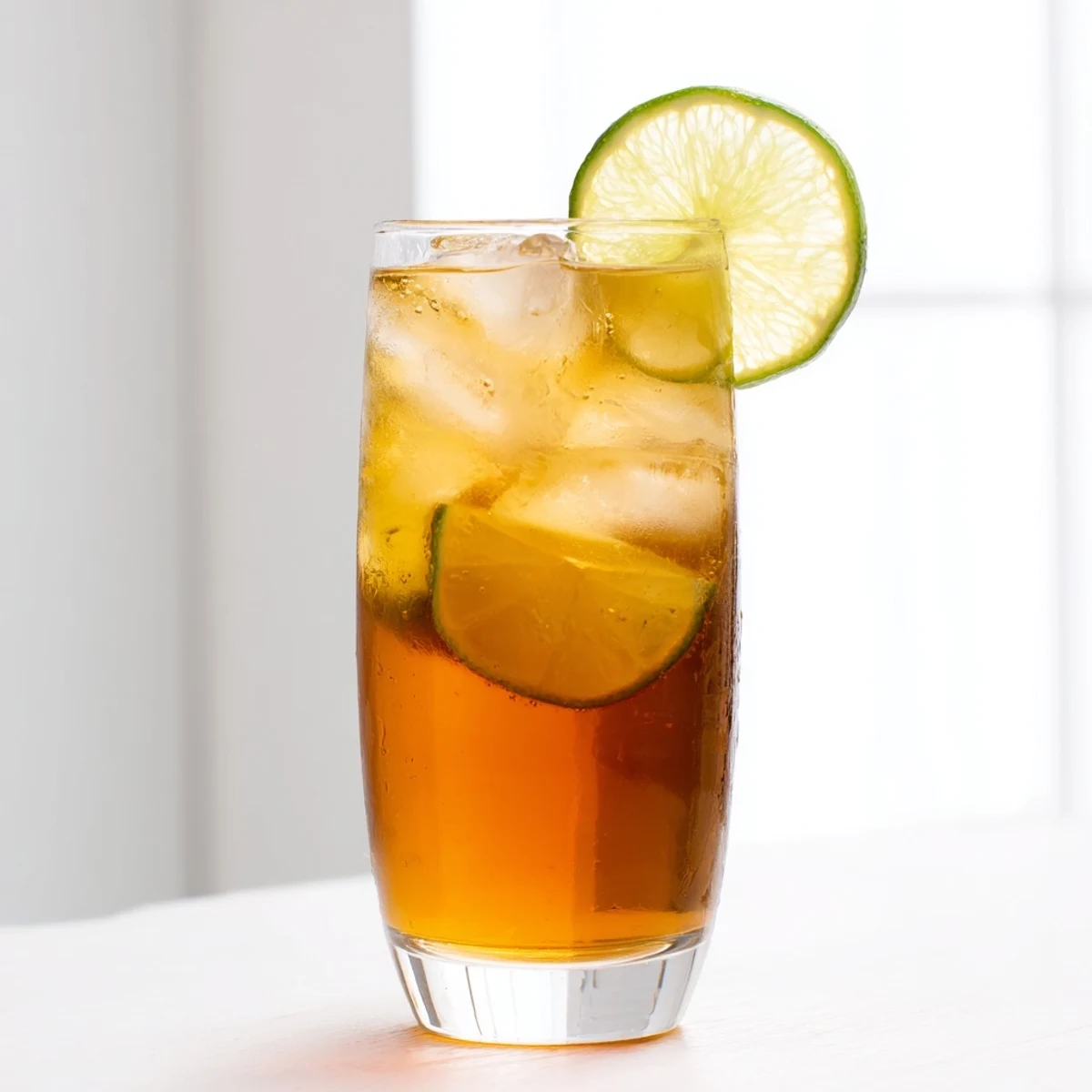 Refreshing glass of Thai lime iced tea with condensation and floating lime wedge garnish