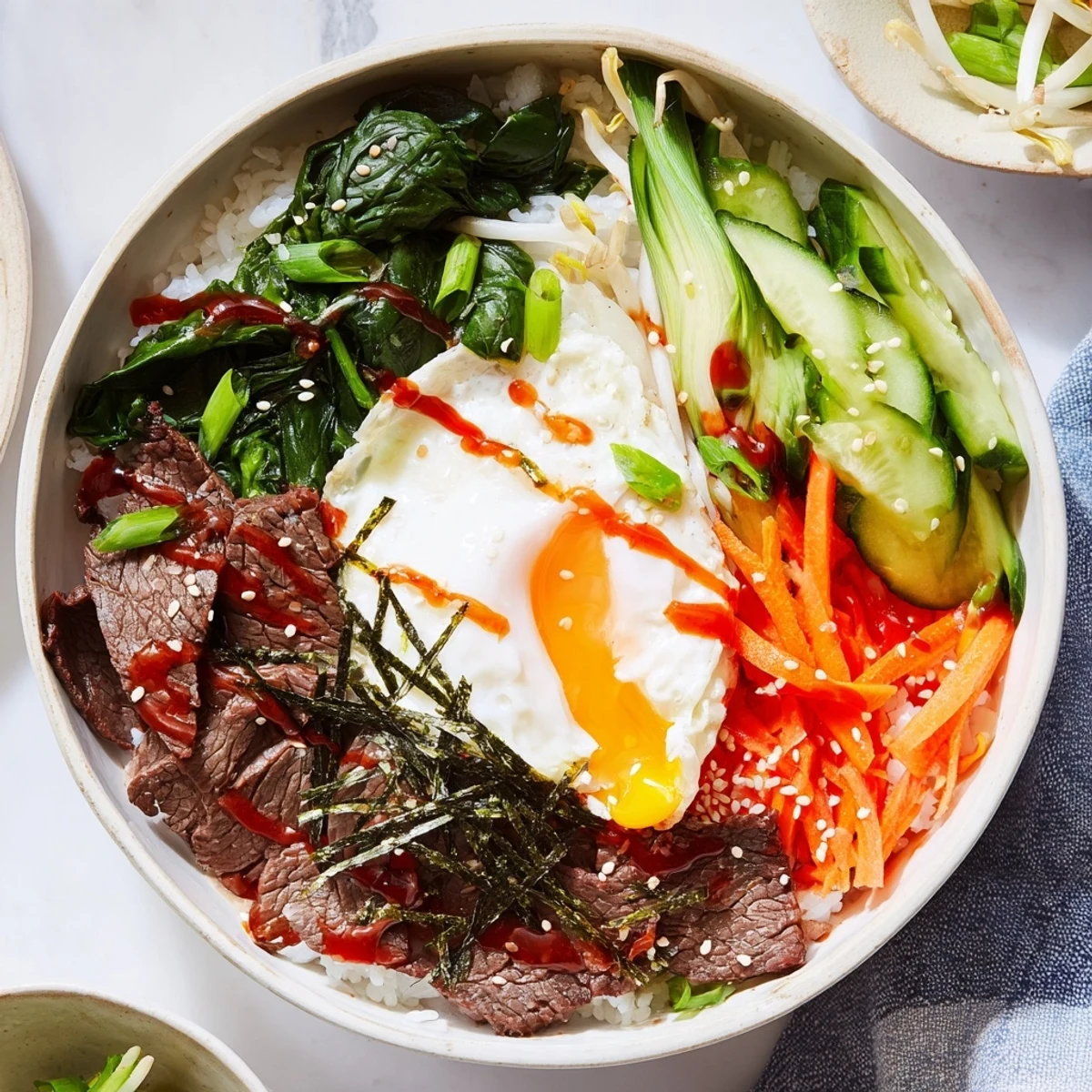Steaming bowl of Korean-Inspired Breakfast Bowl with crispy veggies, savory beef strips, and golden egg yolk