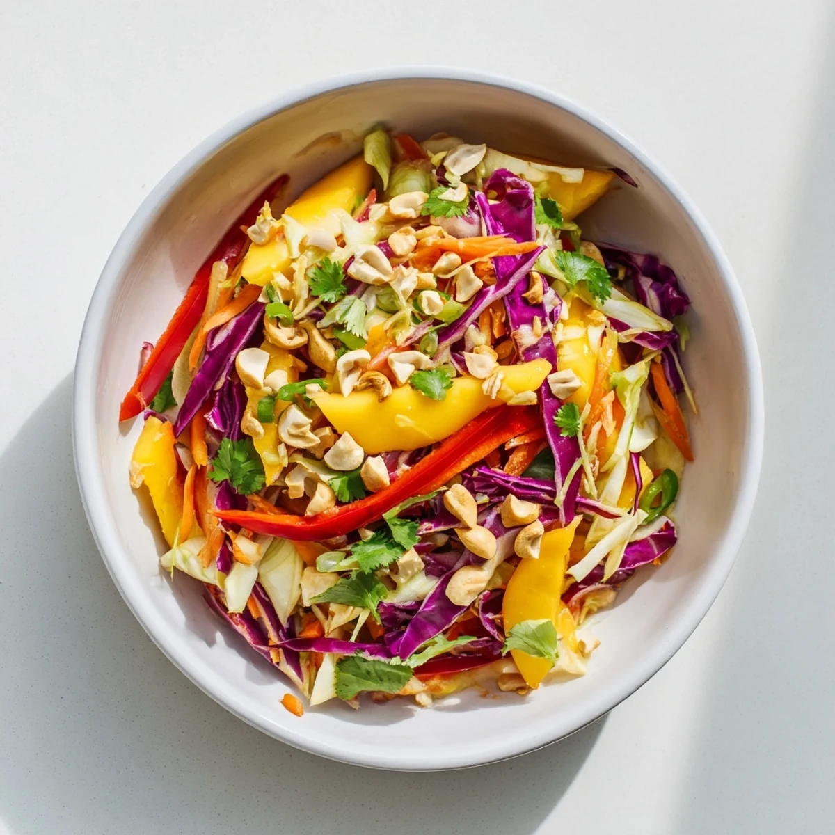Colorful mango slaw topped with toasted cashews and fresh cilantro leaves