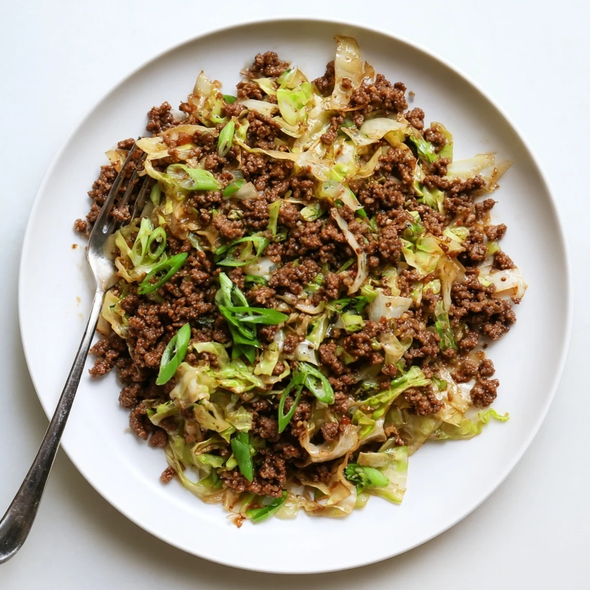 Savory skillet of Mongolian ground beef and cabbage stir-fry topped with fresh green onions