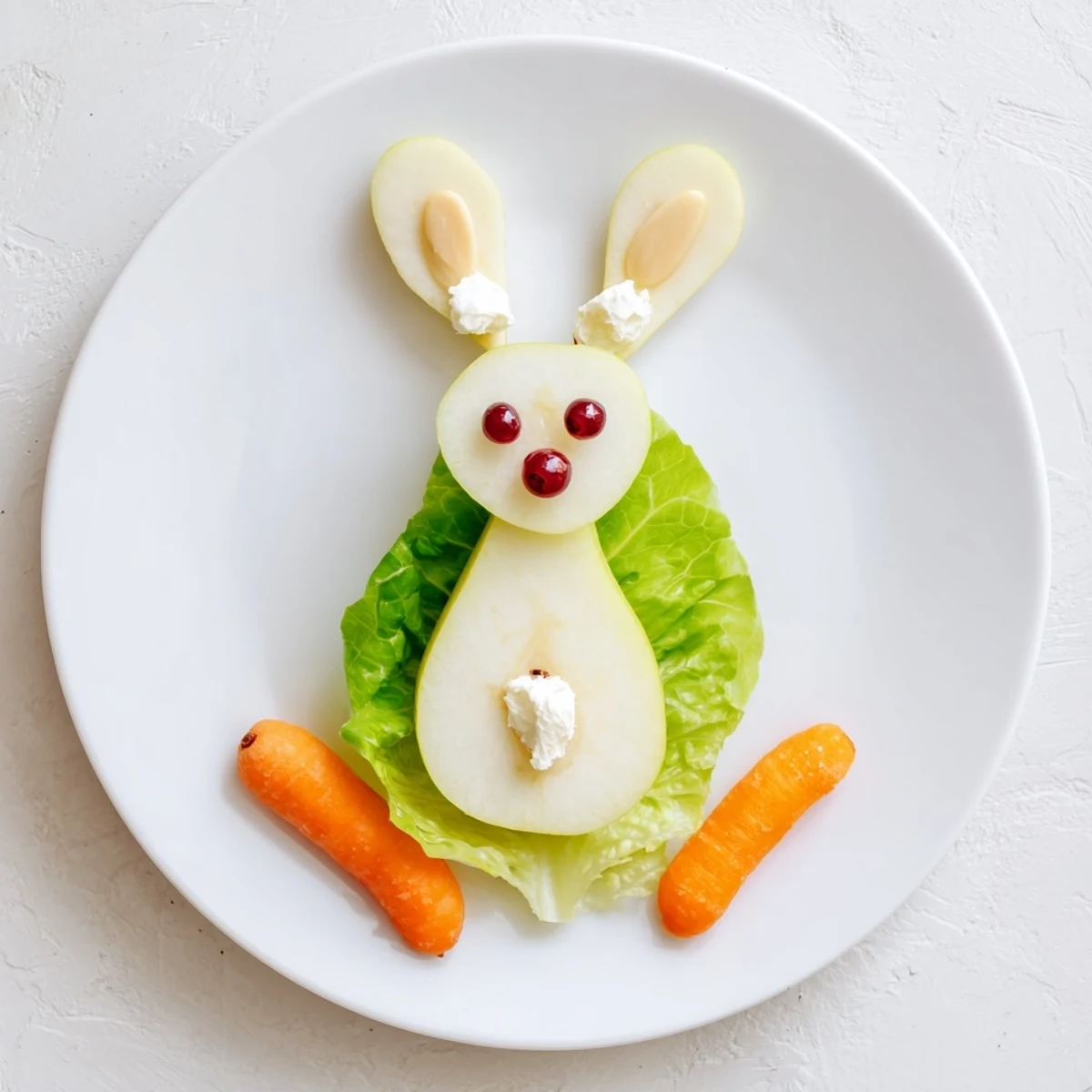 Whimsical pear bunny salad featuring almond ears and cottage cheese tail on fresh lettuce bed