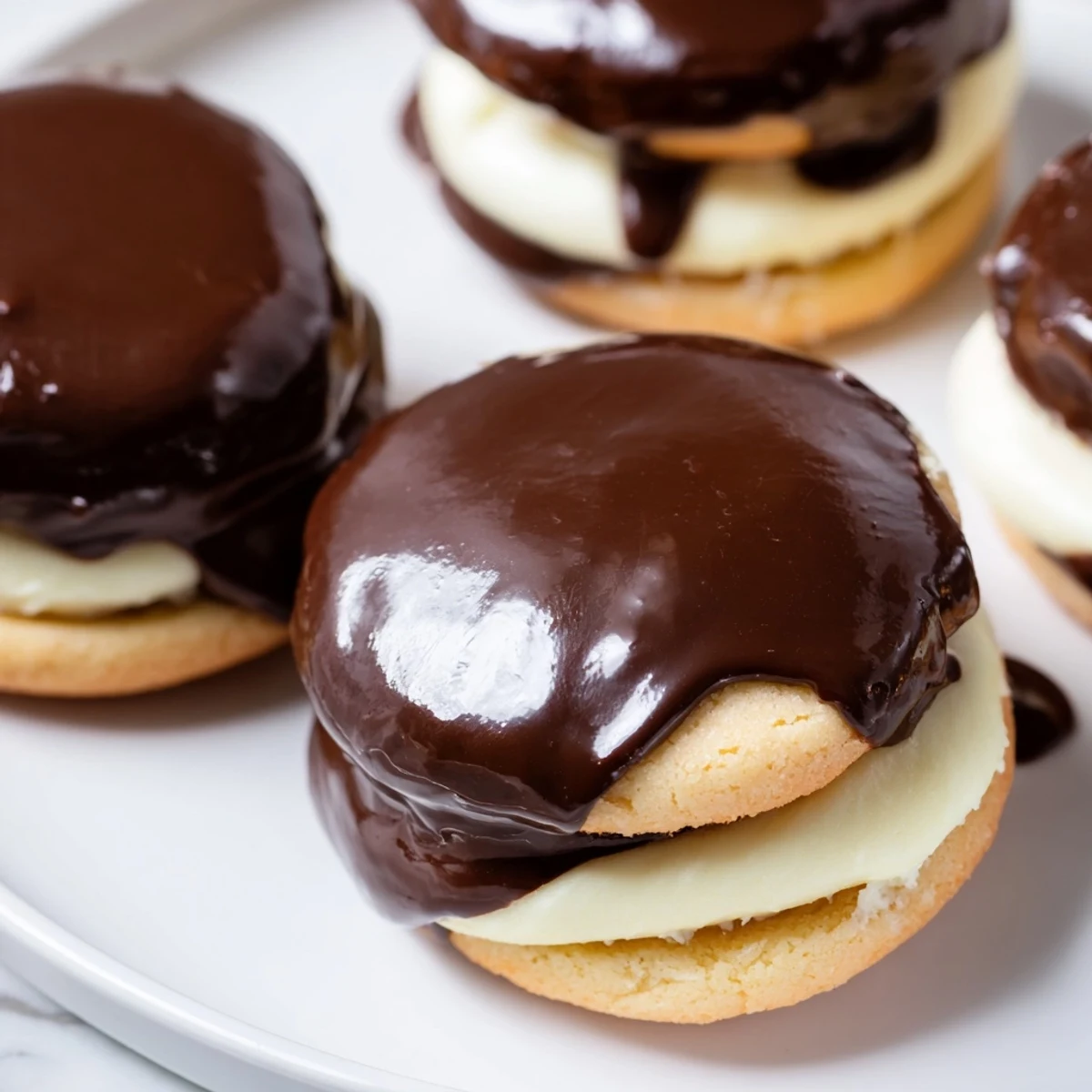 Homemade Boston cream pie cookie bites arranged on a decorative serving platter with chocolate dripping down sides