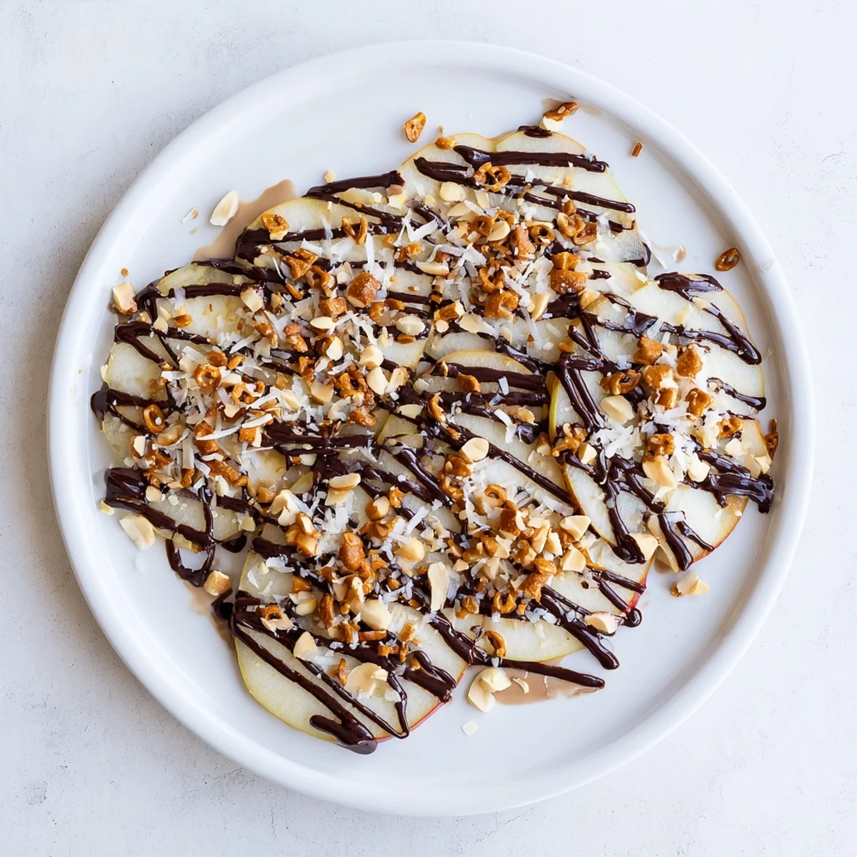Crisp apple wedges topped with creamy peanut butter chocolate sauce and crunchy peanuts
