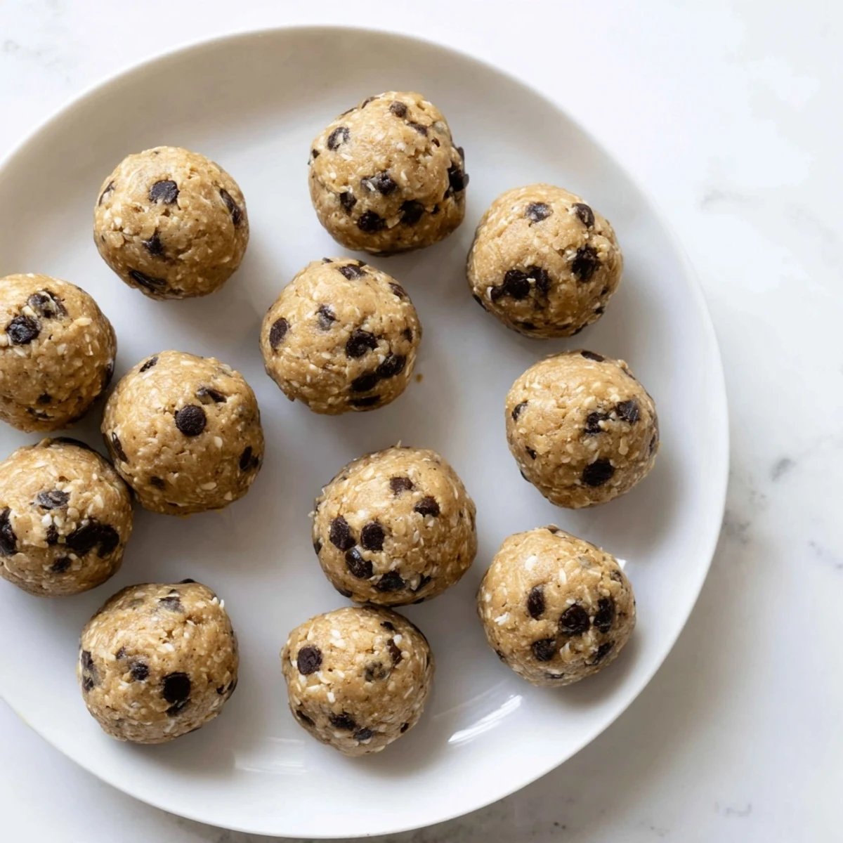 No-bake chocolate chip cookie dough protein balls stacked on a wooden serving board for easy snacking