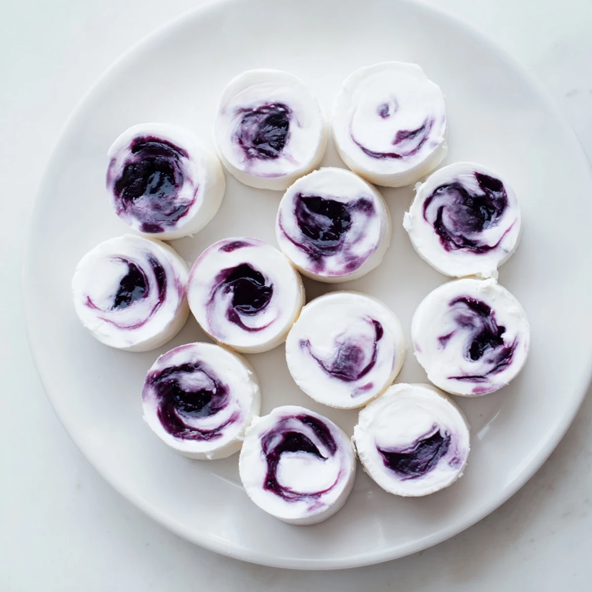 Homemade blueberry swirl yogurt bites served in a chilled white bowl for summer snacking