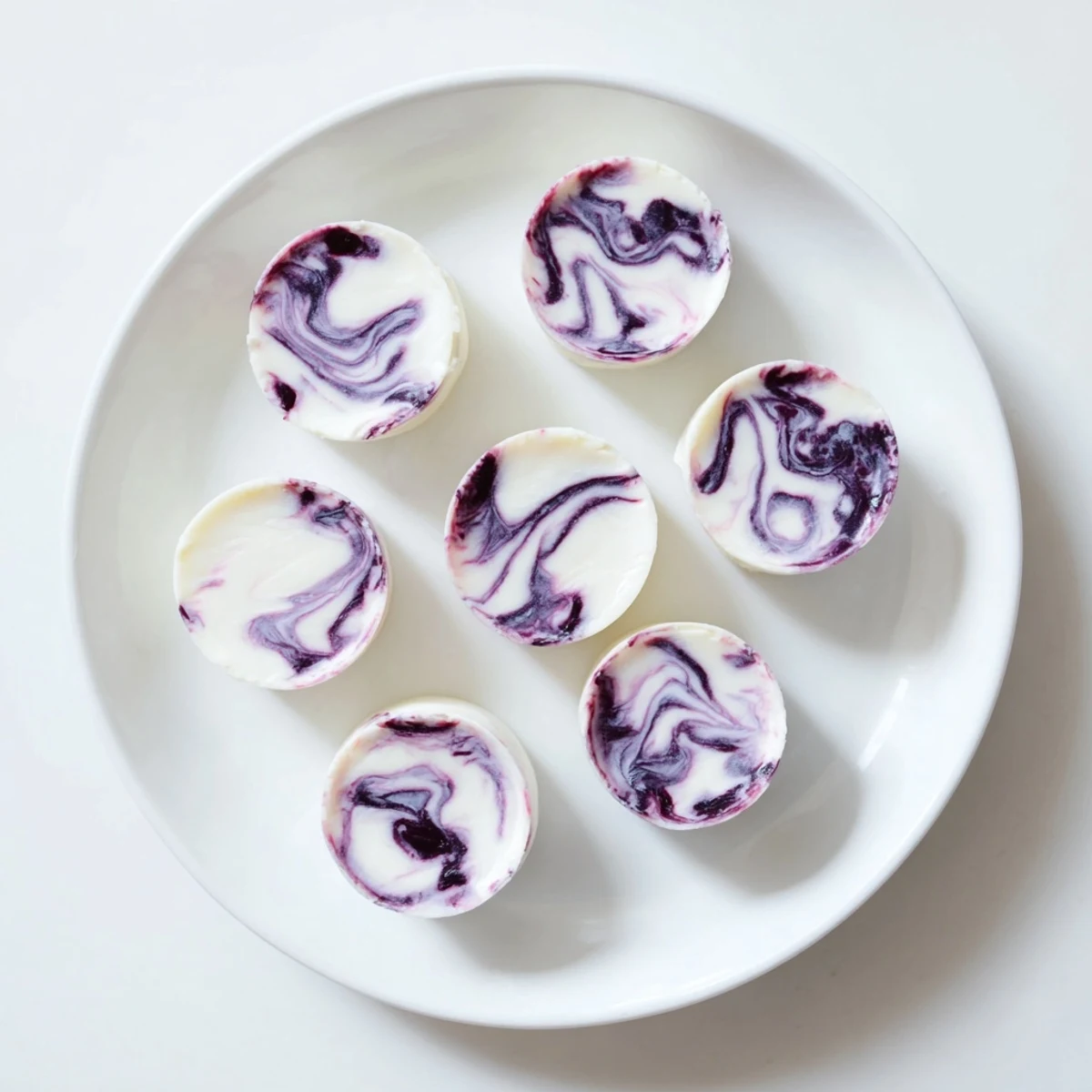Frozen blueberry swirl yogurt bites showing purple ribbons throughout the white Greek yogurt