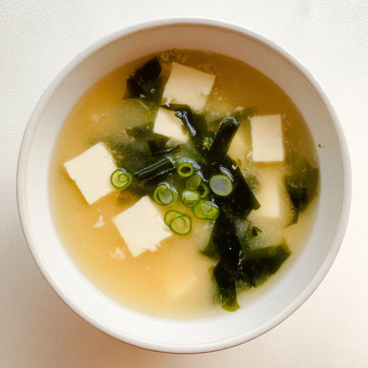 Comforting easy authentic miso soup with tender tofu, savory wakame, and sliced green onions ready for warming meal