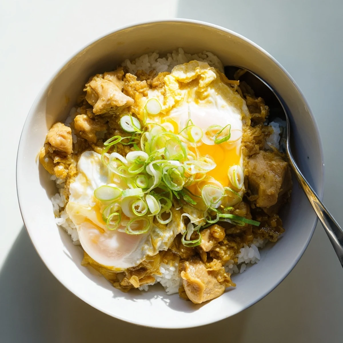 Steaming bowl of Oyakodon featuring fluffy scrambled eggs and tender chicken over fluffy white rice