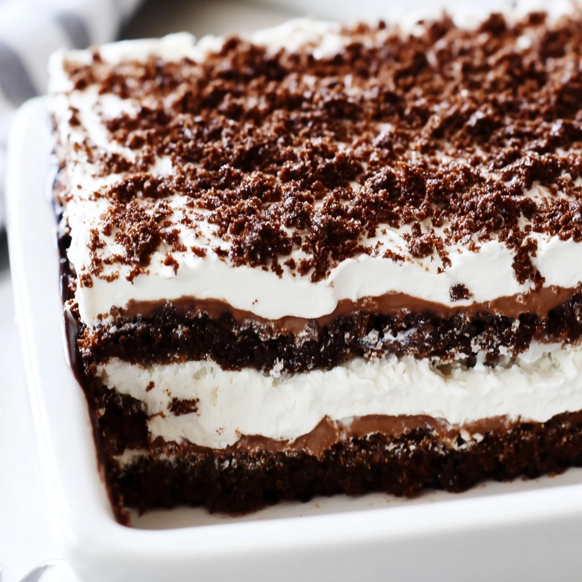 Glass jar displaying layered keto dirt cake with chocolate pudding, whipped cream, and almond crumble topping