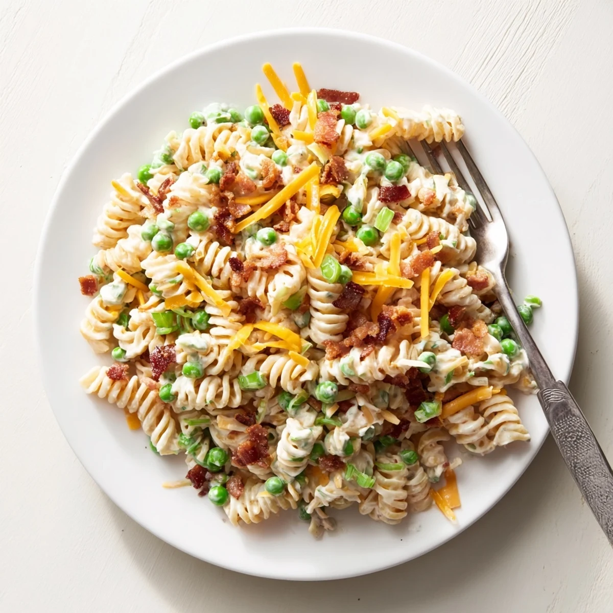 Delicious bacon cheddar pasta salad with tangy ranch coating and green onion garnish on a white plate