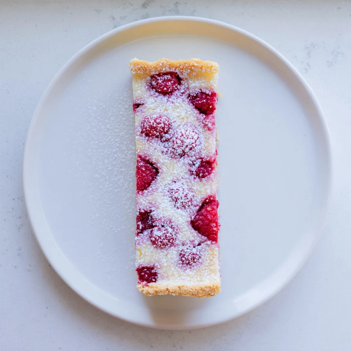 Square lemon raspberry bars arranged on wooden board with bright red berry filling visible
