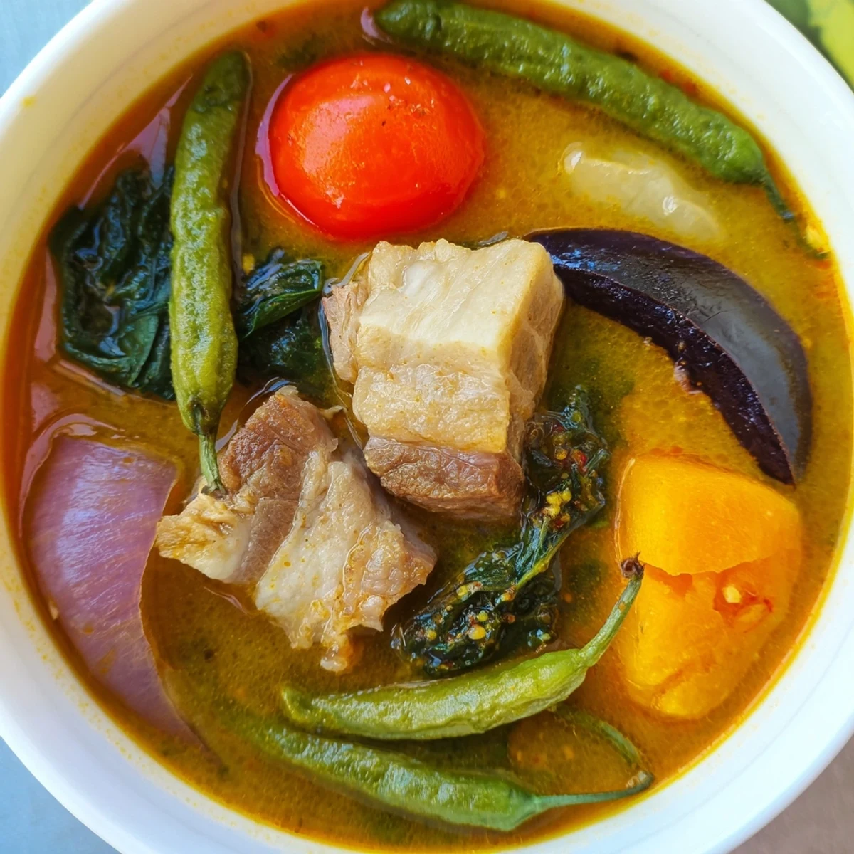 Filipino Sinigang sour soup served piping hot with spinach, radish, and savory pork belly pieces