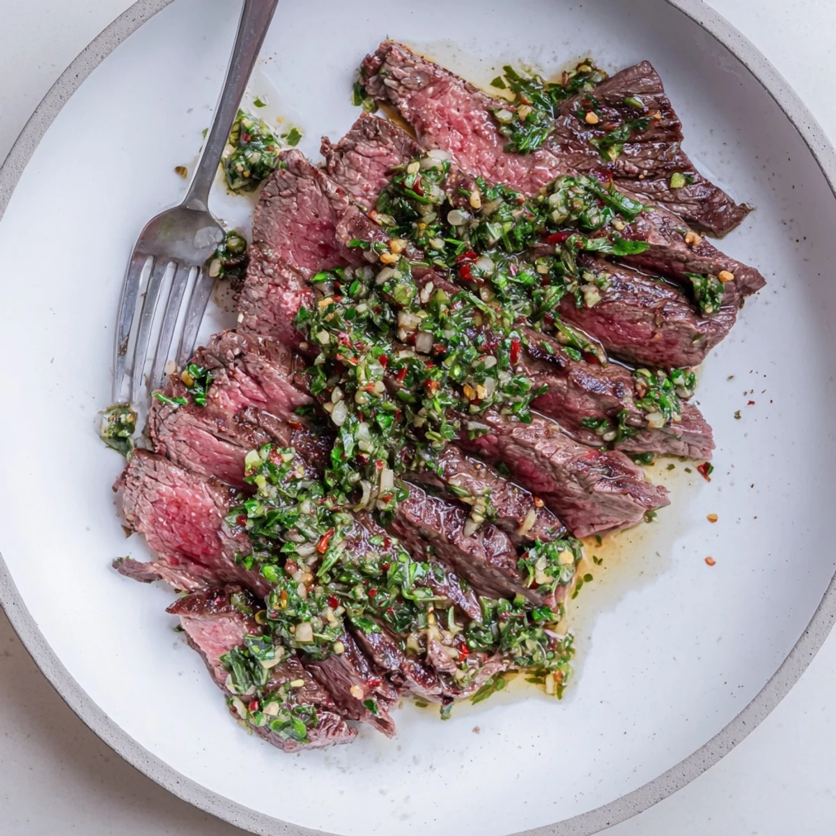 Chimichurri Steak Recipe sliced medium-rare, topped with zesty garlic-parsley sauce.