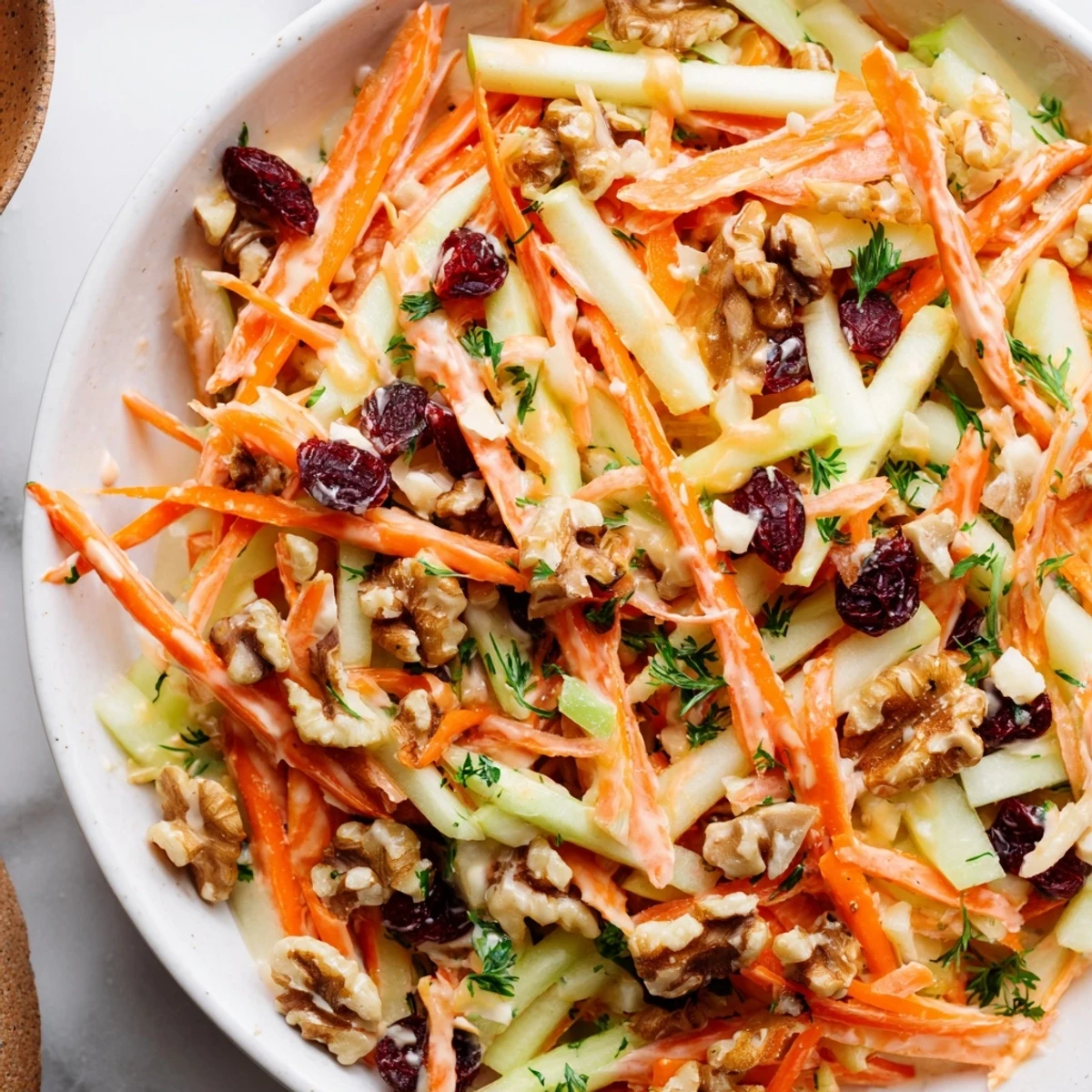 Crunchy Apple Carrot Salad With Creamy Citrus Dressing pictured in bowl, ready to serve