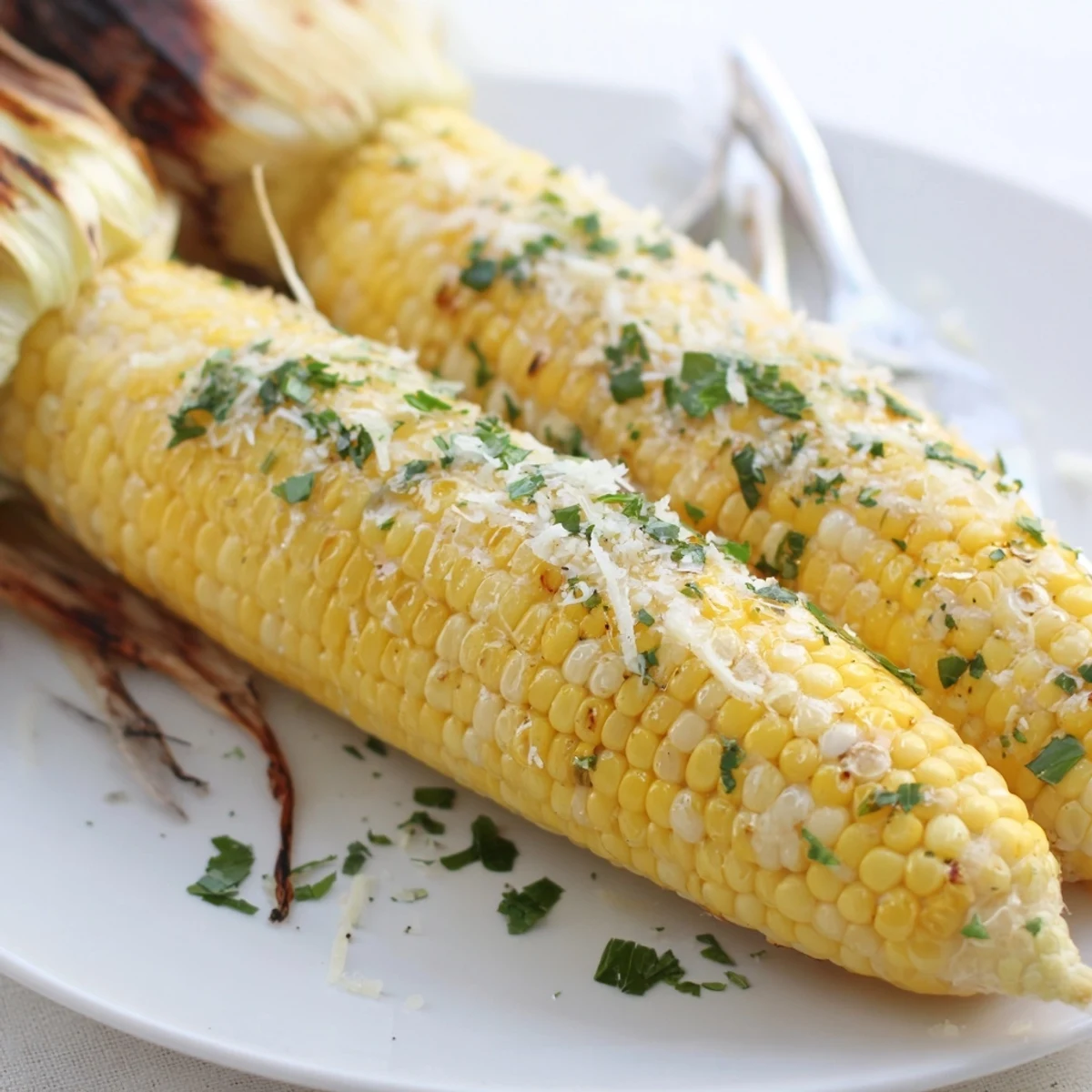 Grilled Garlic Parmesan corn on the cob, butter-brushed with charred kernels.