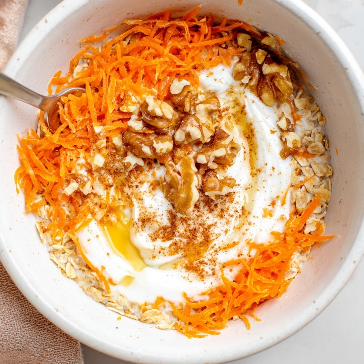 Creamy Carrot Cake Overnight Oats topped with toasted pecans and maple drizzle